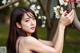 A woman in a purple dress leaning against a tree with white flowers.