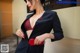 A woman in a black suit with a red button on her chest.