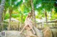 A woman sitting on a rock in front of palm trees.