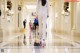 A woman in a white suit walking down a long hallway.