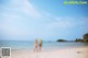 A couple of women standing on top of a sandy beach.