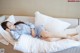 A woman laying on a bed with white pillows.