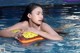 A woman in a swimming pool holding an inflatable toy.