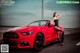 A woman sitting on top of a red convertible car.