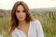 A woman in a white shirt standing in tall grass.