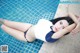 A woman in a blue and white bathing suit laying on the edge of a pool.