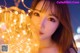 A woman holding a string of lights in front of her face.