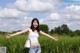 A woman standing in a field with her arms outstretched.