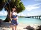 A woman in a blue dress standing on a beach.