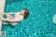 A woman in a white bathing suit is floating in a pool.